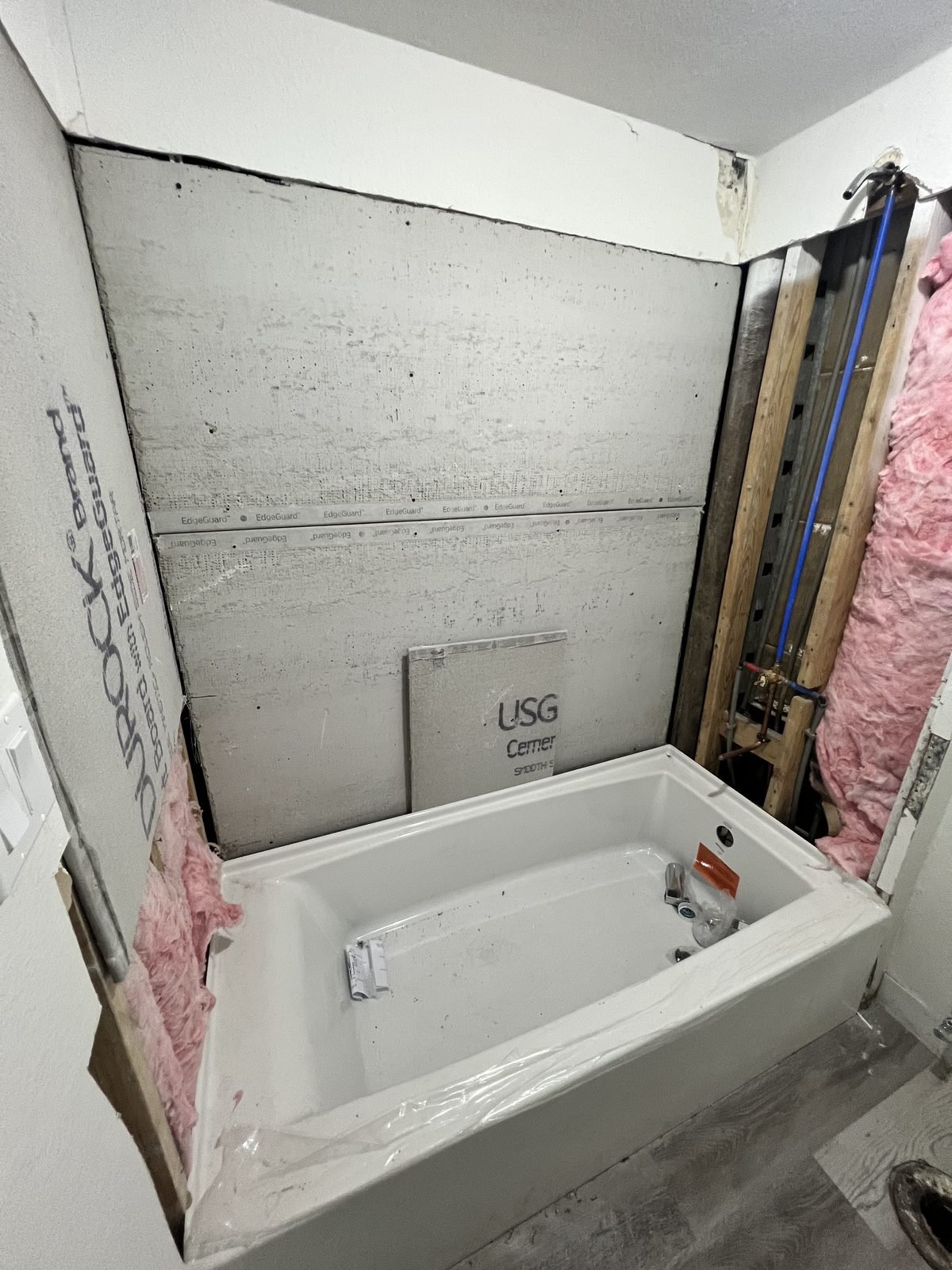 Bathroom before: tub set in open framing and insulation