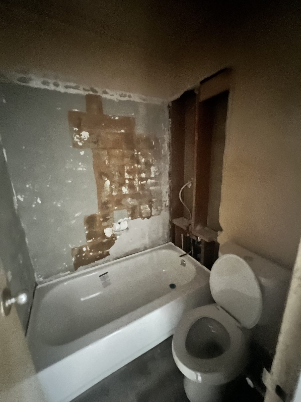 Bathroom before: walls stripped, old tub and toilet